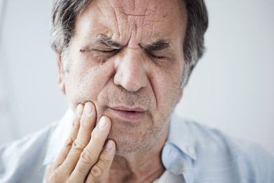 Man holding mouth in pain. Lewis Family & Implant Dentistry provides treatment options for tooth decay in the Vancouver, WA area!