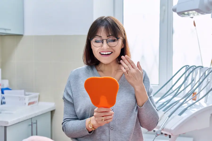 Woman admiring her new smile after successful all-on-4 dental implant procedure at Lewis Family & Implant Dentistry in Vancouver WA