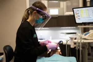 A dental professional from Lewis Family & Implant Dentistry wearing PPE performing a dental implant consultation procedure on a patient
