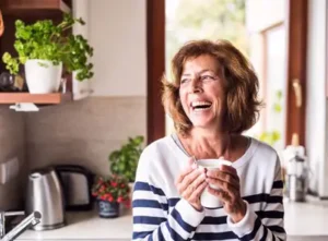 Woman enjoys a cup of coffee and wonders if dentures will change the shape of her face