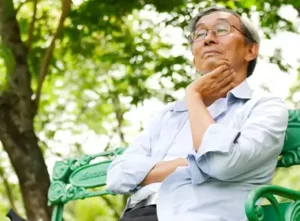 man sitting on park bench contemplating if dentures will make him look older